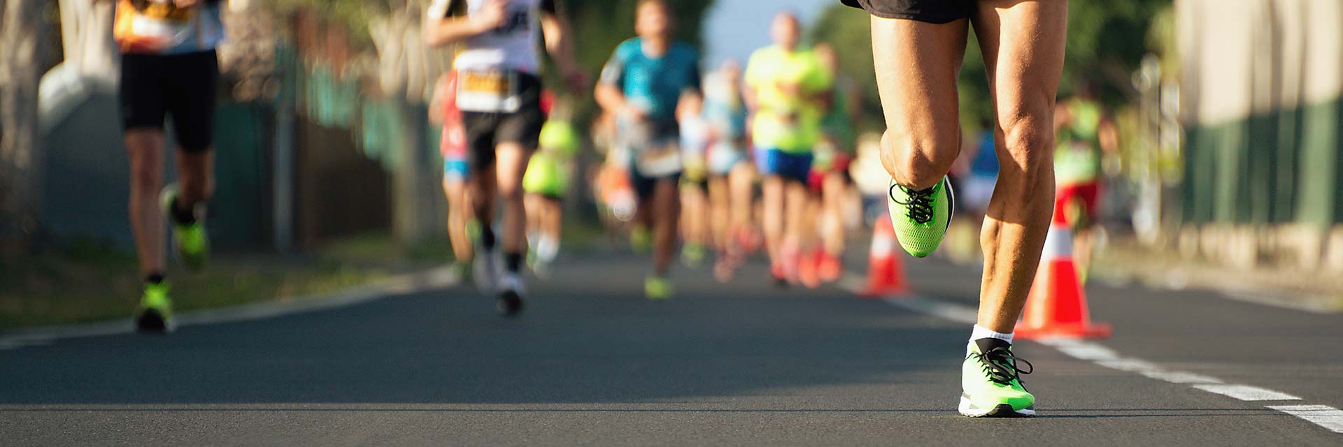 This is an image of multiple runners in a marathon with number bibs and brightly colored running shoes.