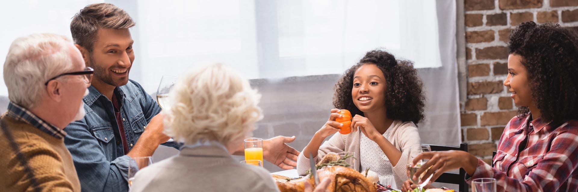 This is an image of a multi-ethnic and multi-generational family having a happy conversation around a dinner table.